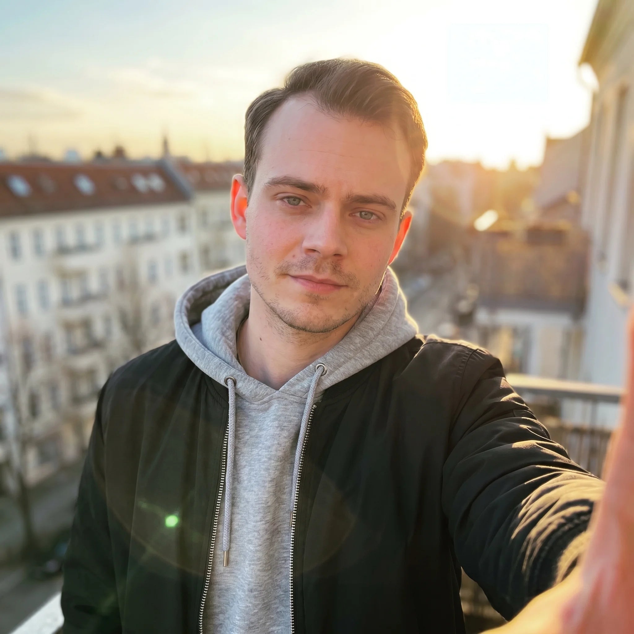 Mann Anfang 30 auf seinem Berliner Balkon zur goldenen Stunde.